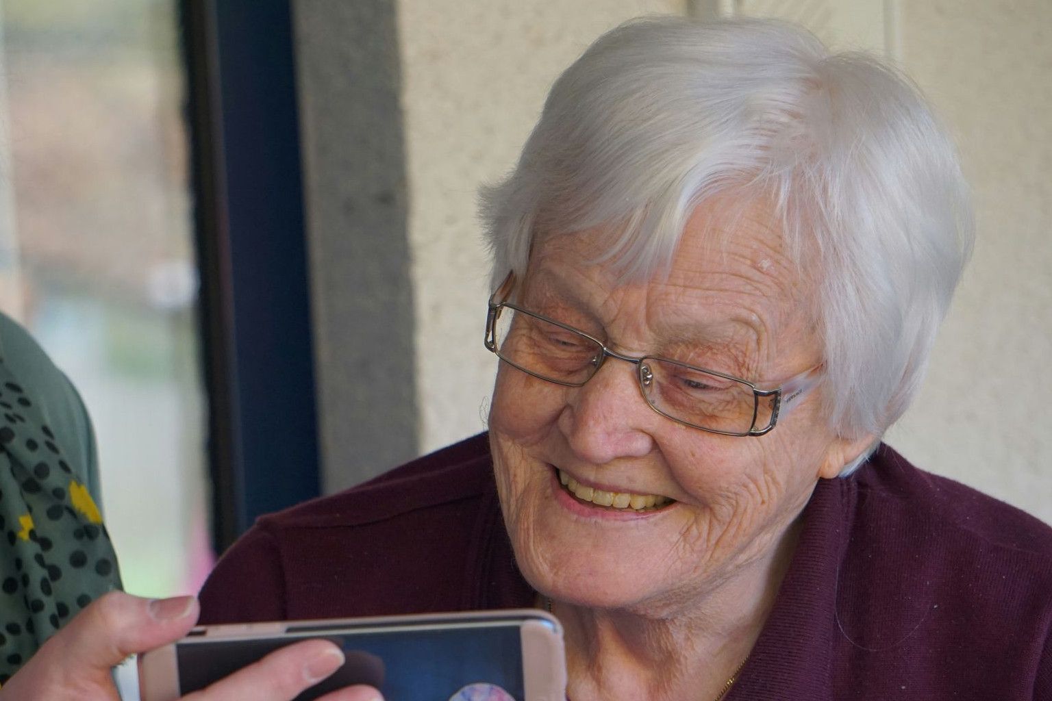 woman in brown button up shirt holding white smartphone